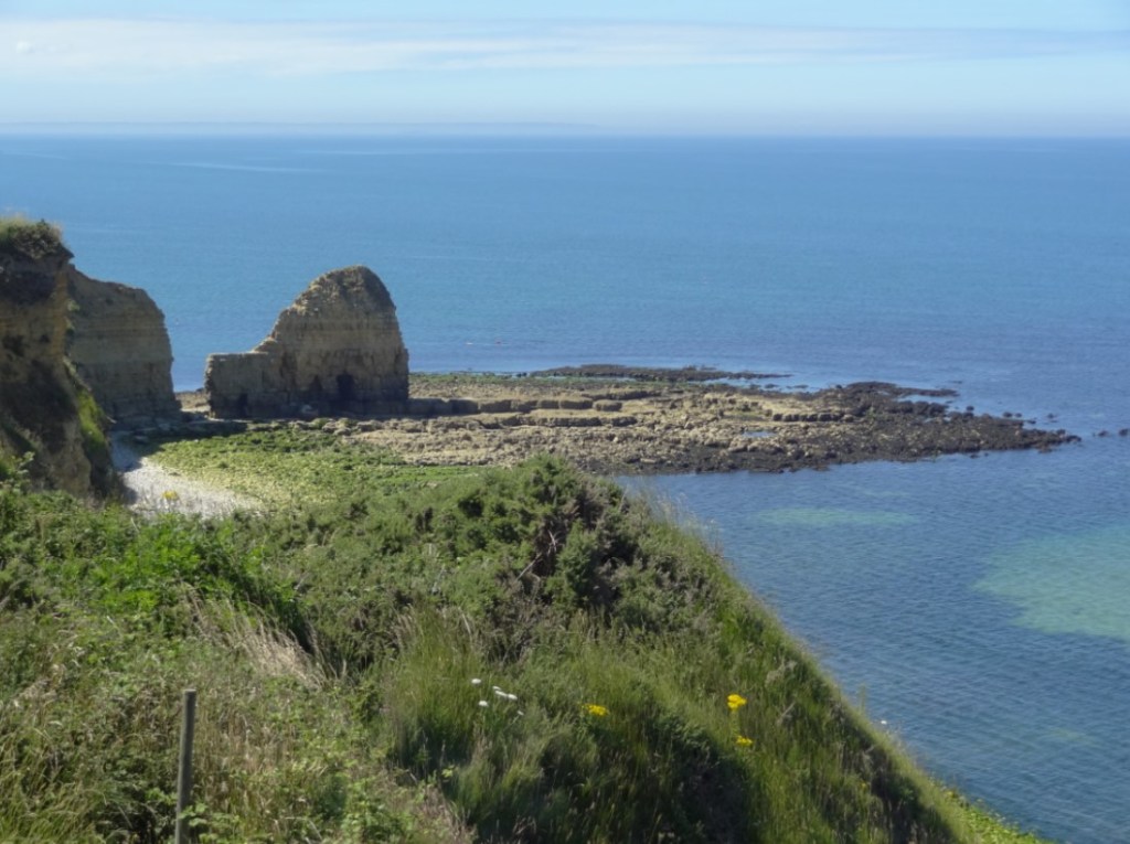 A close up of a hillside next to a body of water
Description automatically generated